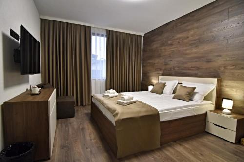 1 dormitorio con 1 cama grande y pared de madera en Libertè suites Velingrad, en Velingrad