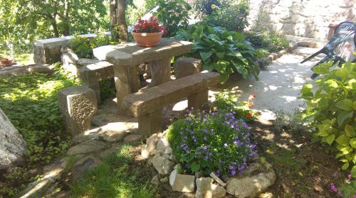 a stone bench in a garden with flowers at Apartment Pud Oreh in Roč