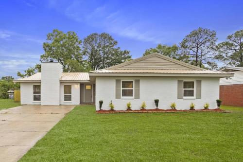 a white house with a green lawn at 4BR Ocean Springs Home with Luxury Amenities in Ocean Springs