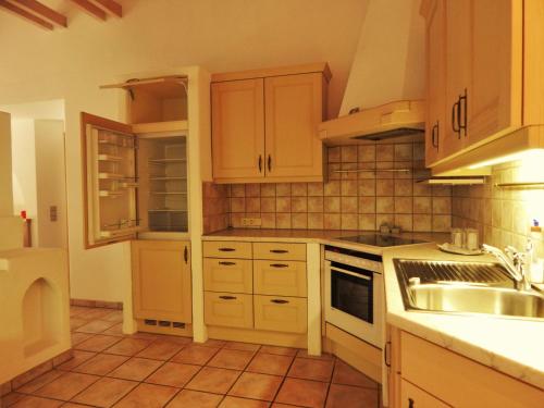 a kitchen with wooden cabinets and a tiled floor at Hotel Königsseer Hof in Schönau am Königssee