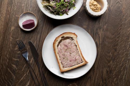 a piece of bread on a white plate with a salad and a sandwich at Hôtel 48°Nord & Restaurant, The Originals Relais in Breitenbach