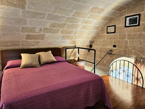 een slaapkamer met een paars bed en een stenen muur bij La Suite Delle Stelle in Matera