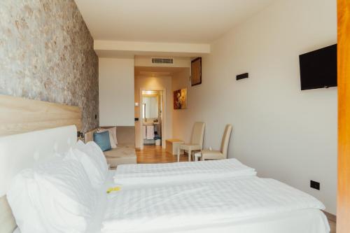 two white beds in a room with a tv at Villa Ersilia in Limone sul Garda