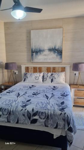 a bedroom with a bed with a blue comforter and two lamps at Albatros 506 in Amanzimtoti