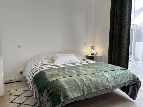 a bedroom with a bed with a green blanket at 669 - Maison 4 personnes en centre bourg d'Erquy in Erquy
