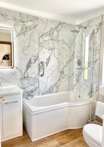 a bathroom with a white tub and a marble wall at Springwood Room Only Accommodation in Seahouses
