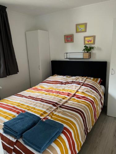 a bed with two blue pillows on it in a room at Het Eikenhuisje in Putten; huisje op de Veluwe. in Putten