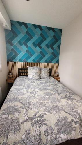 une chambre avec un lit avec une couverture bleue et blanche dans l'établissement Nid douillet plein de charme avec Parking gratuit, à Chantilly