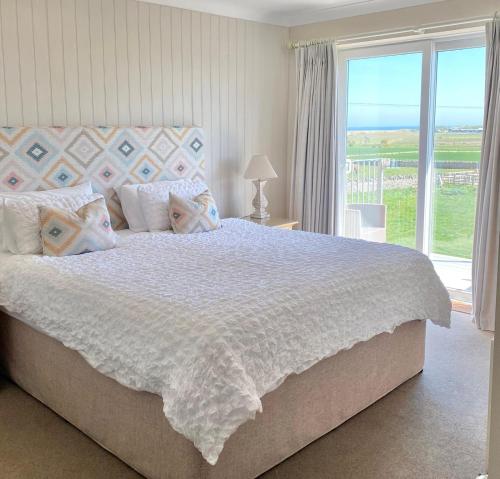 a bedroom with a bed with a view of the ocean at Springwood Room Only Accommodation in Seahouses