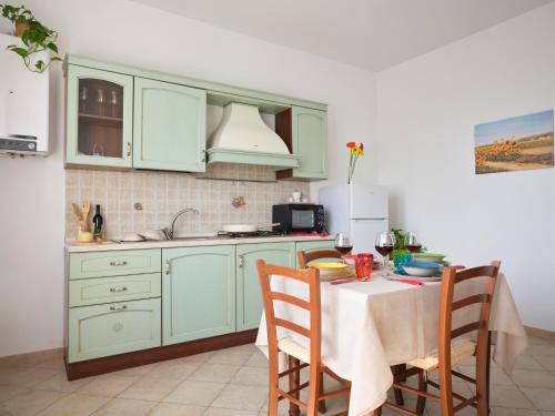 a kitchen with green cabinets and a table with chairs at Casa Vacanze Santa Caterina in Asciano