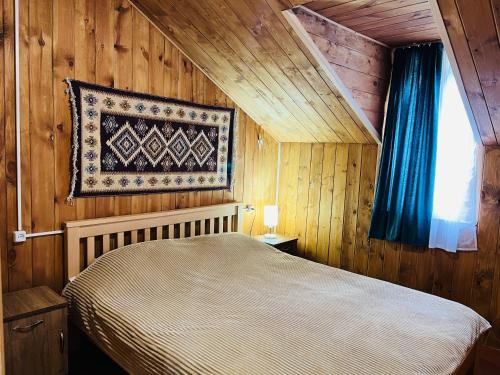 a bedroom with a bed and a rug on the wall at Hotel Arkhoti in Akhieli