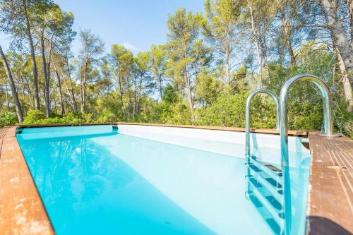 a swimming pool with blue water and trees in the background at Sa Rota de can Xito in Sencelles