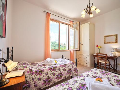 a bedroom with two beds and a desk and a window at Casa Vacanze Santa Caterina in Asciano