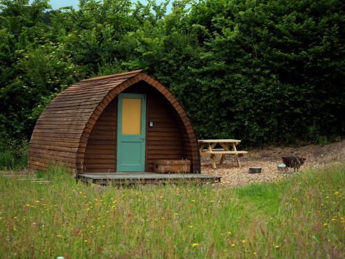 a wooden hut with a door and a picnic table at Hogchester Meadow Pods in Charmouth