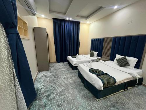 a hotel room with two beds and blue curtains at Quel Serviced Units in Taif