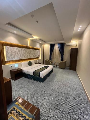 a large hotel room with a bed and a chair at Quel Serviced Units in Taif