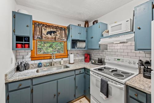 a kitchen with blue cabinets and a stove top oven at Bear Tracks Lodge By Avada Properties in Sevierville