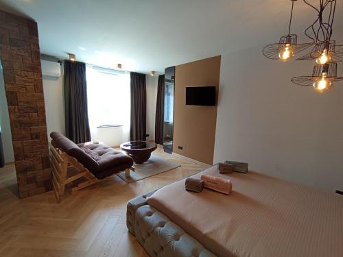 a bedroom with a bed and a couch and a chair at Уютно Студио Verde Suites 07 in Blagoevgrad