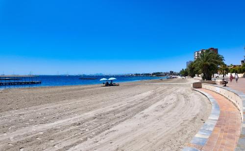 a sandy beach with umbrellas and the ocean at Cactus Apartment La Ribera in Santiago de la Ribera