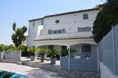 une maison blanche avec des palmiers devant dans l'établissement Belle maison avec piscine dans les hauteurs à Saint Raphael, à Saint-Raphaël