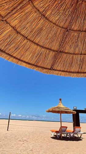 two chairs and an umbrella on a beach at Casabay Appart Vue Sur Piscine in Sidi Rahal