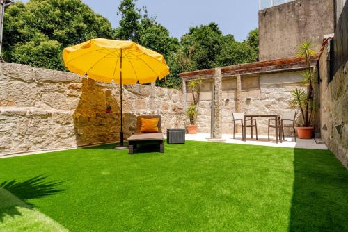 Una sombrilla amarilla y una silla en el césped. en Gardenia Urban Retreat, en Oporto