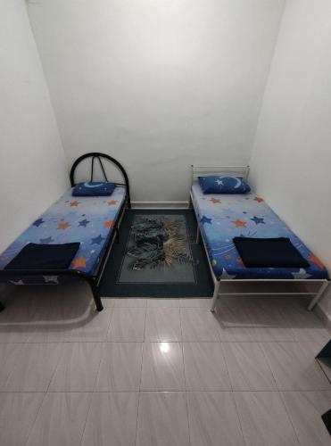 two twin beds in a small room withthritisthritisthritisthritisthritisthritisthritisthritis at Seri Homestay in Alor Setar