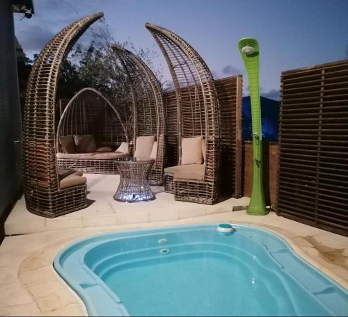 a swimming pool with wicker chairs and a hot tub at VILLA La DOLCE VITA in Sainte-Marie