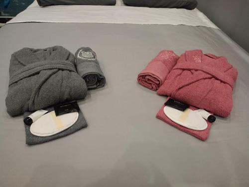 - un lit avec deux serviettes et une paire de chaussons dans l'établissement Artemis Luxus Home and Spa Alexandroupolis City Faros, à Alexandroúpolis
