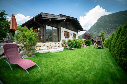 a yard with lawn chairs and a house with a building at Ferienhaus Ötztal-Lodge in Sautens
