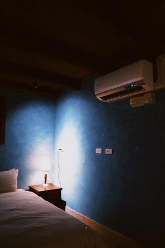 a bedroom with a blue wall with a bed and a lamp at 牧嶼 Nomads' Isle in Jinhu