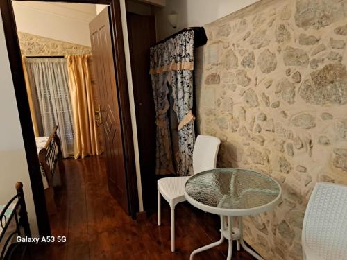 a room with a table and chairs and a stone wall at Suita Kallia in Patsídhes