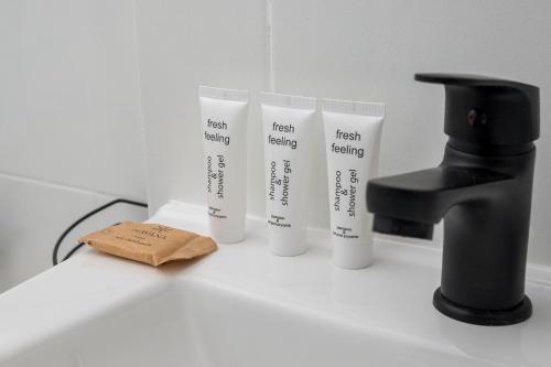a bathroom counter with three test bottles and a faucet at 8th Floor City View Apartment by BookingHost in Warsaw