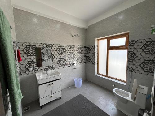 a bathroom with a sink and a toilet and a window at Skyline Homestay in Leh
