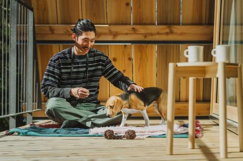 a man sitting on the floor with a dog at SANU 2nd Home 軽井沢1st in Oiwake
