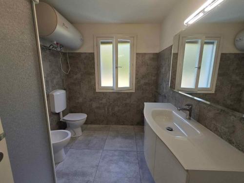 ein Badezimmer mit Waschbecken, Toilette und Spiegel in der Unterkunft Holiday home in Isola di Albarella 43996 in Palazzo Vianello