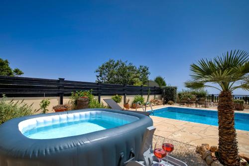 a pool with a hot tub next to a palm tree at Seaview Villa in Peyia | Private pool & jacuzzi by VICHY Holidays in Paphos