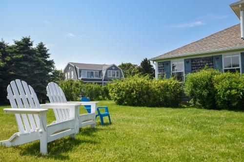 two white chairs sitting in the grass in front of a house at Steps to Nauset Beach Private Yard in Orleans