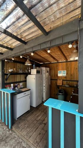 une cuisine avec des appareils électroménagers bleus et blancs et des murs en bois dans l'établissement Hoya Surf Camp - Activités + logements, à Biscarrosse
