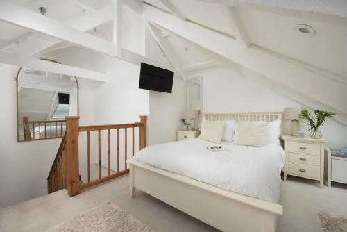 a bedroom with a large white bed and a staircase at Fond Memories Cottage, The Digey, St Ives in St Ives