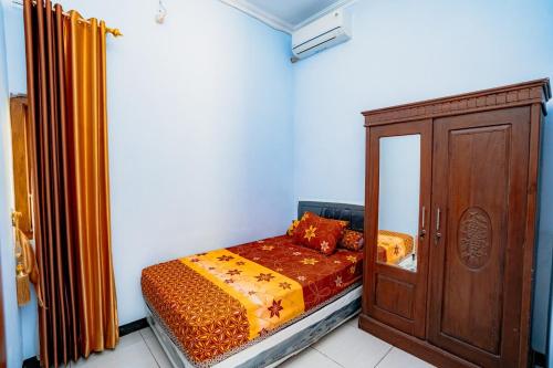 a small bedroom with a bed and a wooden cabinet at Guesthouse Andalusia Gontor 1 Ponorogo in Ponorogo