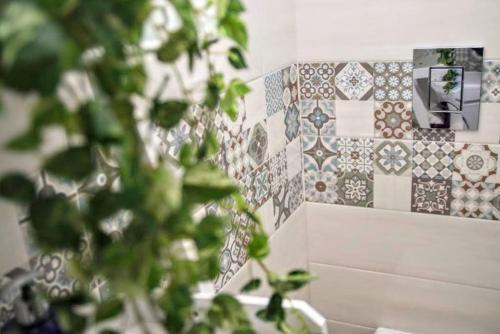 une salle de bain avec un mur carrelé et une plante dans l'établissement Appartamento L'airone Balestrate, à Balestrate