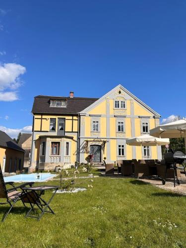 a large yellow house with a yard with chairs at CG Haensch in Großschönau