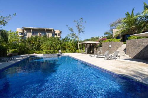 a large blue swimming pool next to a building at La Perla 161-Oceanview,Penthouse,Walking Distance in Tamarindo