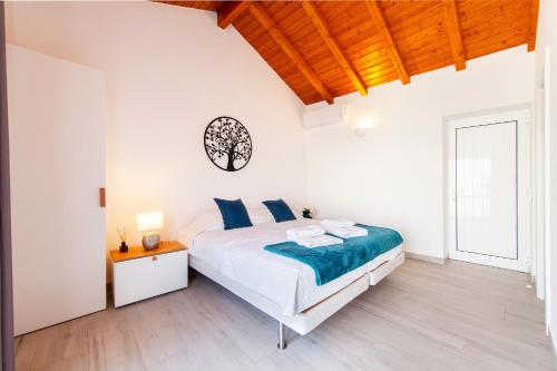 a white bedroom with a bed and a wooden ceiling at Alegria's House in Odiáxere