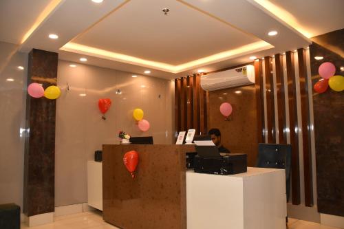 a man sitting at a reception desk with balloons at Hotel Ratneswar in Alīpur Duār