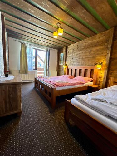 a bedroom with two beds and a wooden wall at Penzion Slovakia in Ždiar