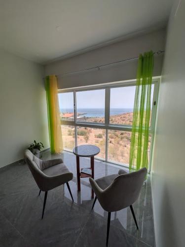 a room with two chairs and a table and a large window at Mirage in Tarrafal