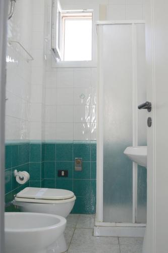 a green and white bathroom with a toilet and a sink at AP Apartment - Baia Verde in Baia Verde