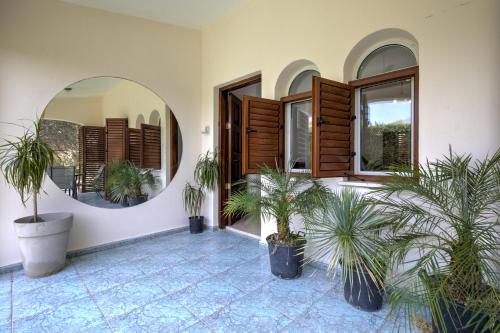 a room with two potted plants and a mirror at Coral Bay Avenue Villa by Vichy Holidays in Paphos